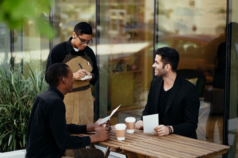 Servers Kneeling at the Table to Take Your Order