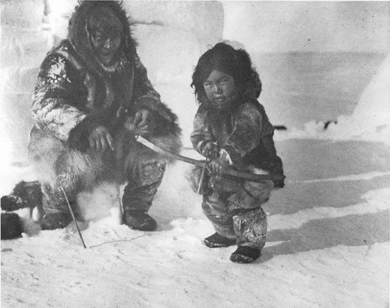Inuit man teaching a boy to shoot a bow (circa 1920)
