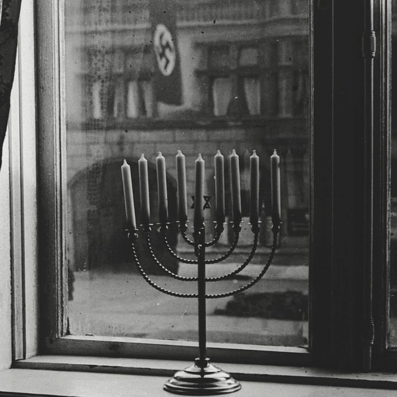 Hanukkah lamp defiantly displayed under a Nazi swastika (1931)