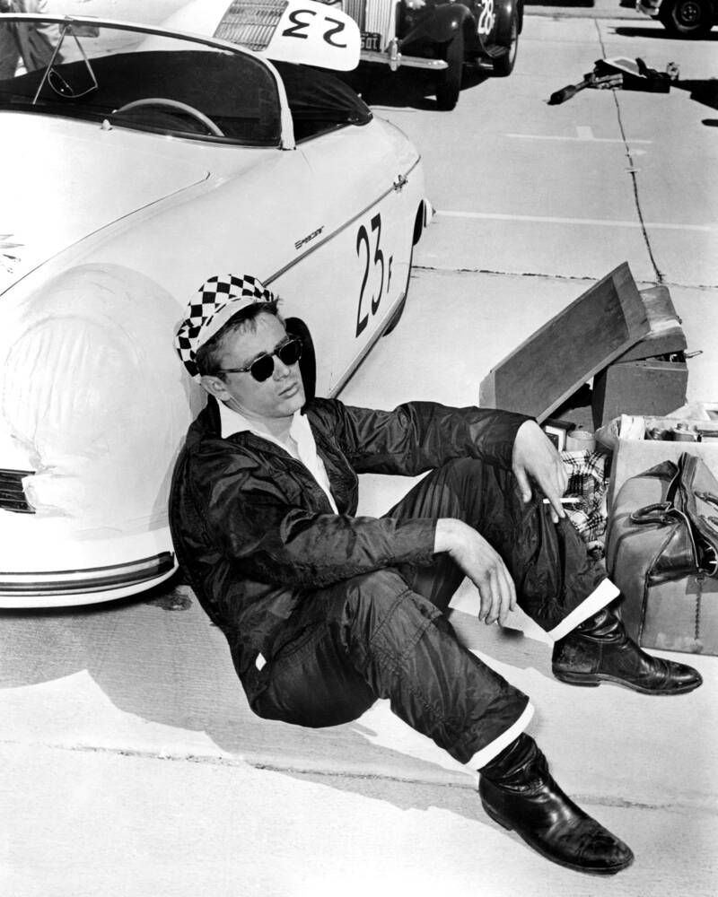 James Dean – Leaning against his Porsche 550 Spyder in a white tee and sunglasses.